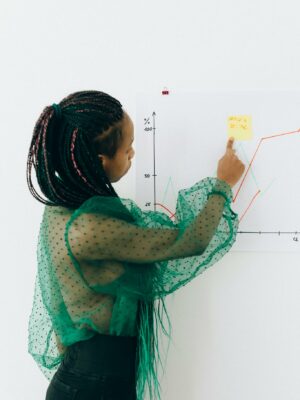 Focused woman points to financial graph, showcasing analysis & strategy.